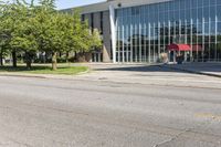 a large, open building with large windows on the ground and street near it with trees