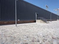 a brick building with glass windows and sidewalk leading to it and a black fire hydrant
