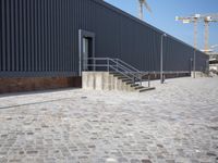 a brick building with glass windows and sidewalk leading to it and a black fire hydrant