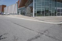 a long building with glass doors next to a street and cars driving by them on the other side