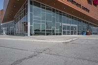 a long building with glass doors next to a street and cars driving by them on the other side