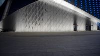 an architectural building with white bricks and blue lights in the background of this photo,