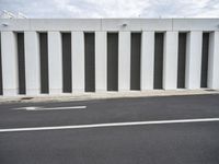 the corner of a parking lot on a sunny day with shutters closed and the ground is gray and there is a white line on the pavement