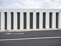 the corner of a parking lot on a sunny day with shutters closed and the ground is gray and there is a white line on the pavement
