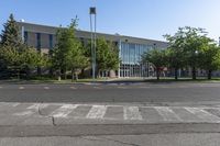 an empty parking lot with some buildings in the background of the photo, with trees and bushes in front