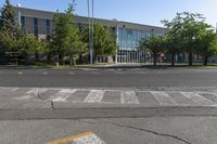 an empty parking lot with some buildings in the background of the photo, with trees and bushes in front