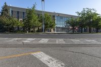 an empty parking lot with some buildings in the background of the photo, with trees and bushes in front