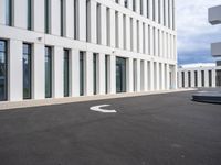 a paved parking lot with an open white building to the side and a white circle at the end