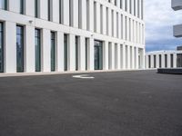 a paved parking lot with an open white building to the side and a white circle at the end