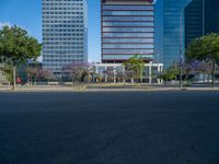 an empty street in front of a building and trees on the other side of the road