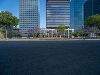 an empty street in front of a building and trees on the other side of the road