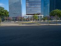 an empty street in front of a building and trees on the other side of the road