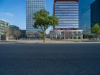 an empty street in front of a building and trees on the other side of the road