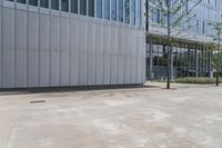 the sidewalk in front of a large building is empty and the grass grows near it