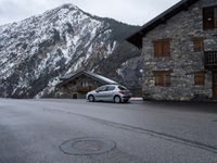 the small car is parked in front of a building near a mountaintop lodge near a gas - trap