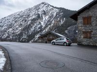 the small car is parked in front of a building near a mountaintop lodge near a gas - trap