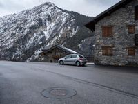 the small car is parked in front of a building near a mountaintop lodge near a gas - trap