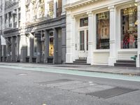 a small dog walking on a sidewalk with two people watching him as another person walks