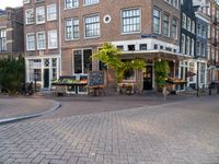 a small restaurant with patio furniture and an umbrella over it's head in a town street