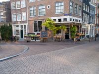 a small restaurant with patio furniture and an umbrella over it's head in a town street