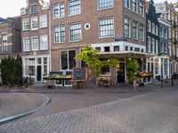 a small restaurant with patio furniture and an umbrella over it's head in a town street