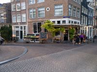 a small restaurant with patio furniture and an umbrella over it's head in a town street