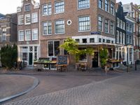 a small restaurant with patio furniture and an umbrella over it's head in a town street