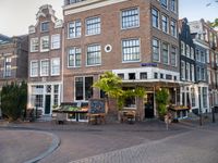 a small restaurant with patio furniture and an umbrella over it's head in a town street