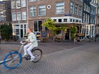 a small restaurant with patio furniture and an umbrella over it's head in a town street