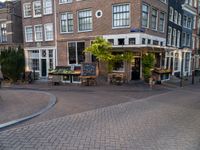 a small restaurant with patio furniture and an umbrella over it's head in a town street