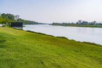 a small tv is sitting on a small hill near the water and grass is growing