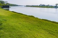 a small tv is sitting on a small hill near the water and grass is growing