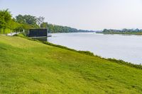 a small tv is sitting on a small hill near the water and grass is growing