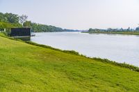 a small tv is sitting on a small hill near the water and grass is growing