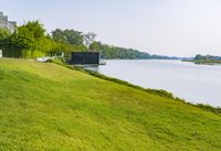 a small tv is sitting on a small hill near the water and grass is growing