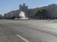 a small water fountain spews out over a city street and traffic lights in the background