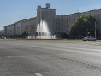 a small water fountain spews out over a city street and traffic lights in the background