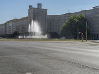 a small water fountain spews out over a city street and traffic lights in the background