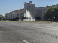 a small water fountain spews out over a city street and traffic lights in the background