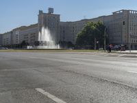 a small water fountain spews out over a city street and traffic lights in the background