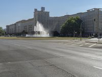 a small water fountain spews out over a city street and traffic lights in the background