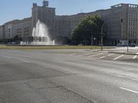 a small water fountain spews out over a city street and traffic lights in the background