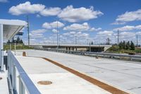 a small white bus shelter on an overpass over a bridge and a highway that passes through