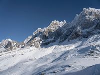 people wearing snow skis on snow covered mountains near clouds and blue sky on a sunny day