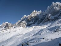 people wearing snow skis on snow covered mountains near clouds and blue sky on a sunny day