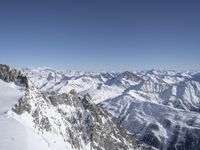 an airplane flying in the sky above a snow covered mountain range next to snow capped mountains