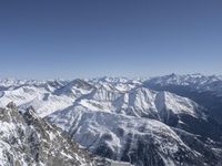 an airplane flying in the sky above a snow covered mountain range next to snow capped mountains