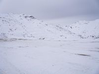 a couple snowboards is laying in the snow on a road in front of mountains