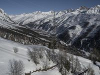 a ski slope with a wooden bench sitting next to it in the snow near mountains