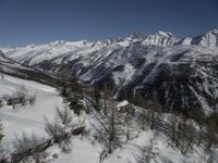 a ski slope with a wooden bench sitting next to it in the snow near mountains